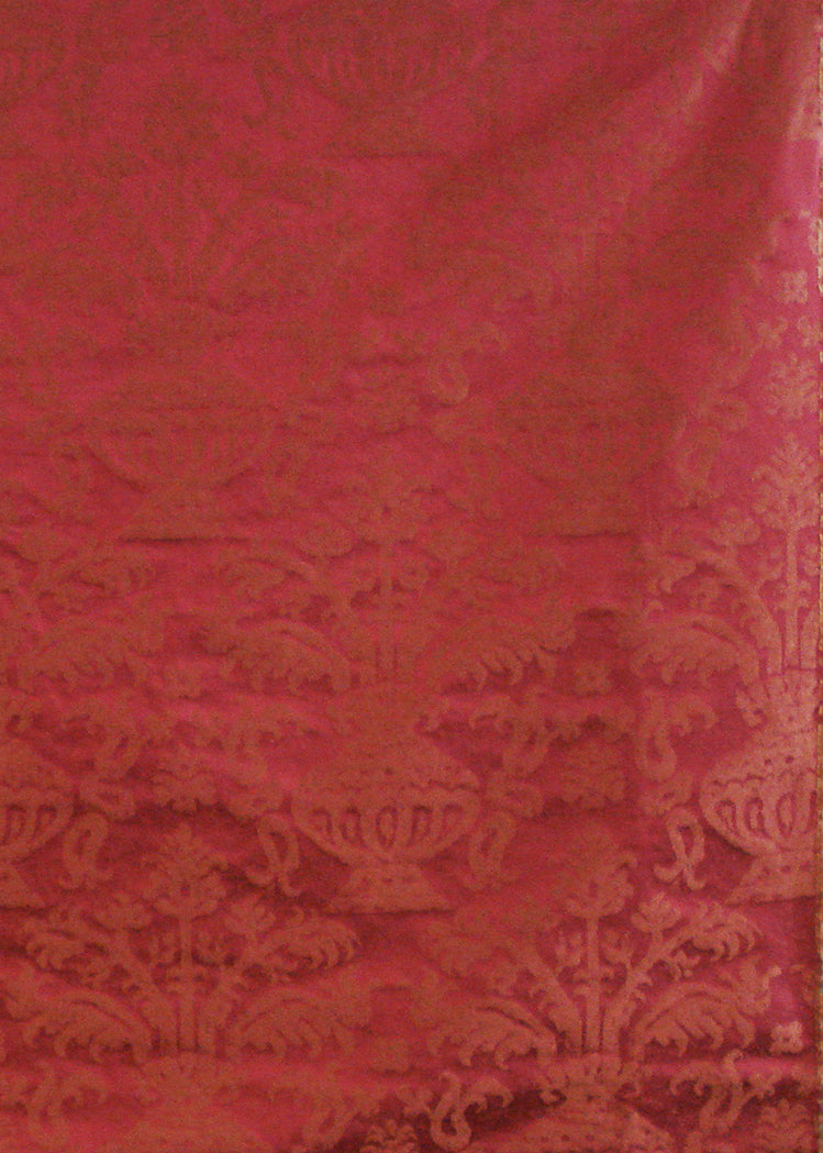 red fabric with a damask pattern that depicts an abstract vase holding branches