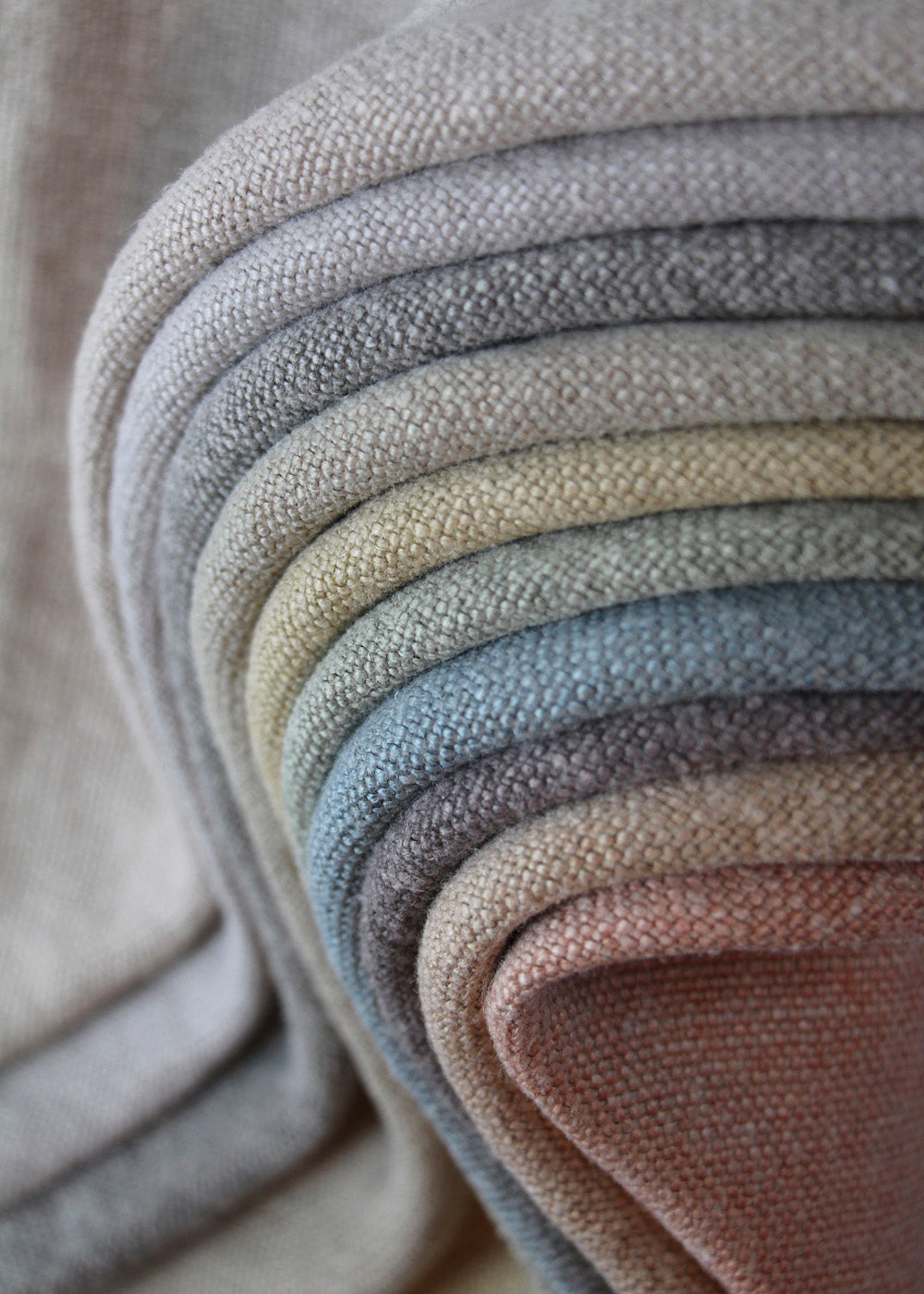 a stack of soft colored linen fabrics in many colors