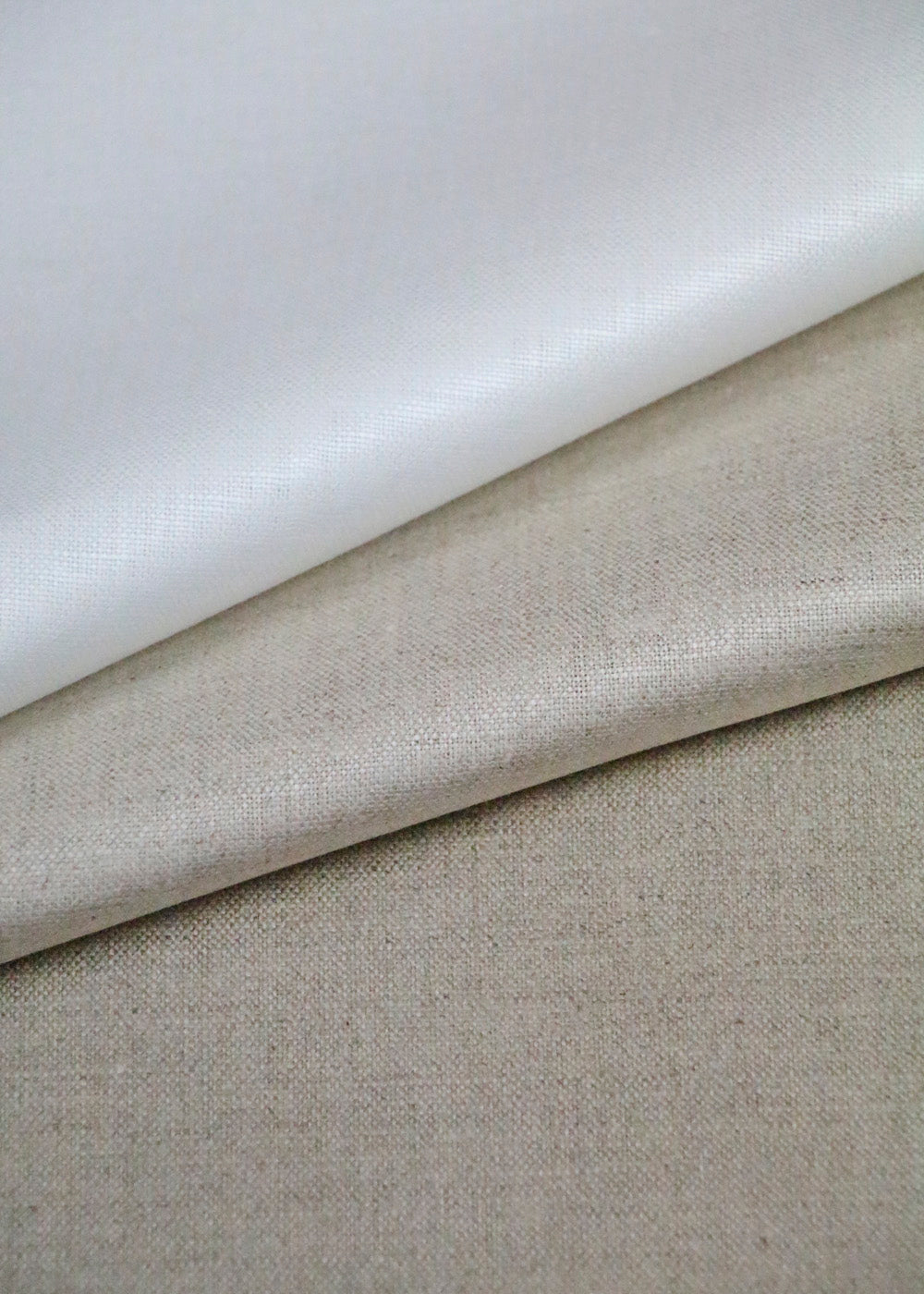 stack of linen fabrics with a luminous glazed finish, shown in three different colors