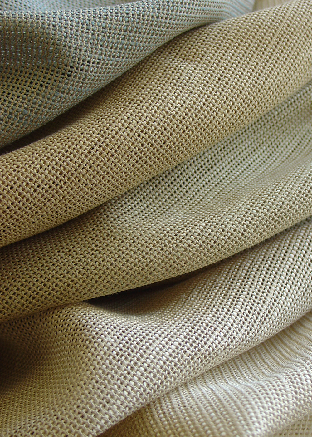 a stack of open-weave linen fabrics in different colors