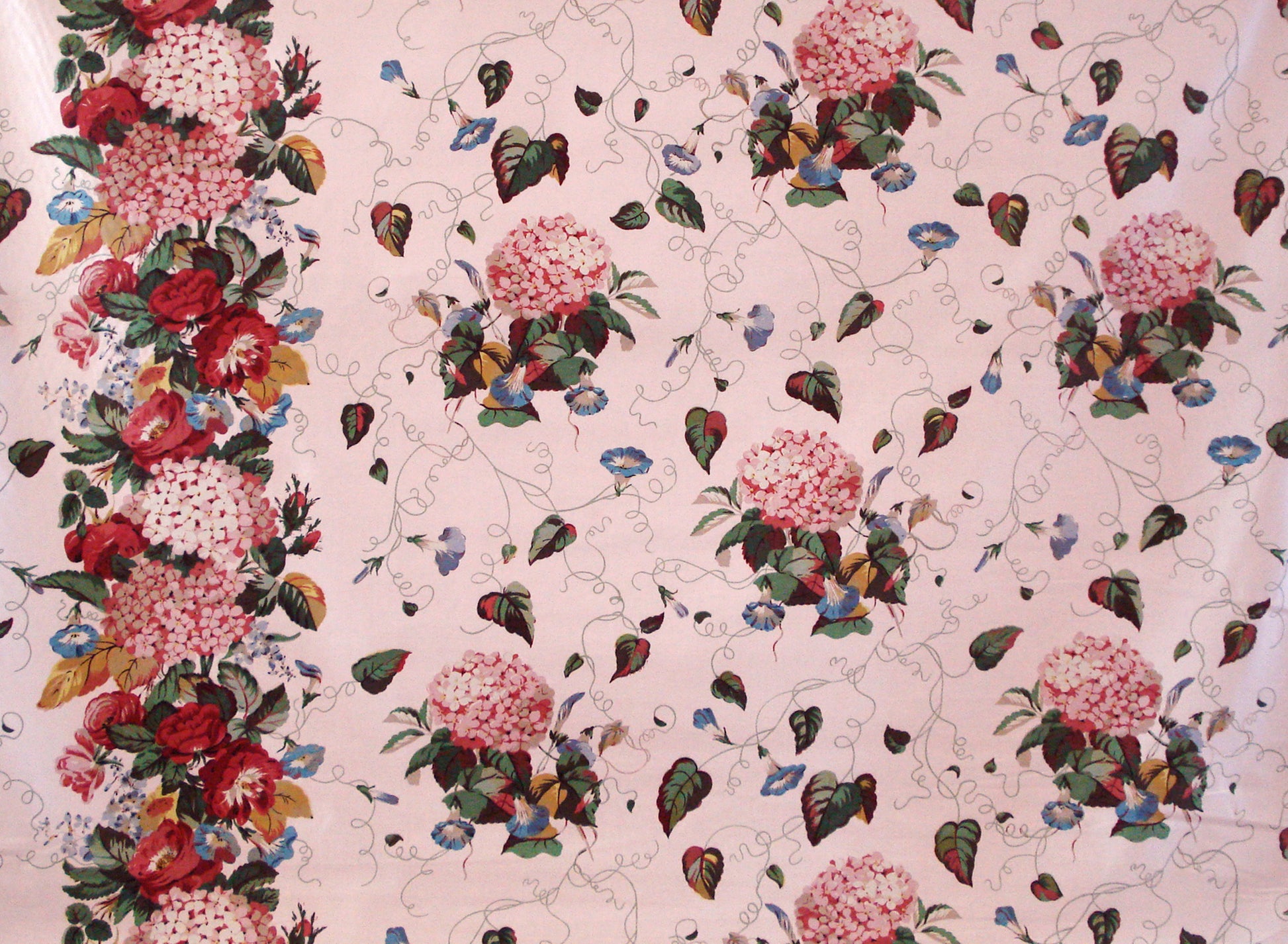 pink fabric printed with bunches of hydrangeas, and a border strip of dense floral print