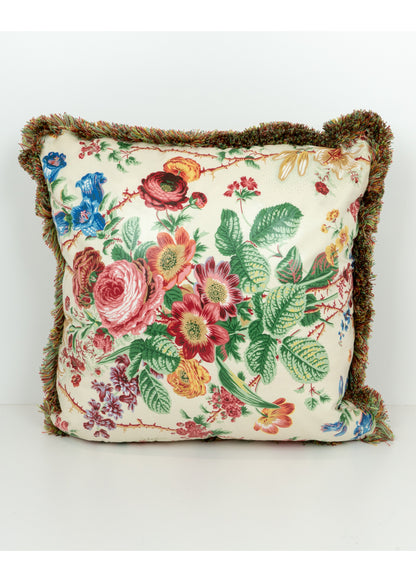 pillow printed with colorful garden florals and a fringe trim\